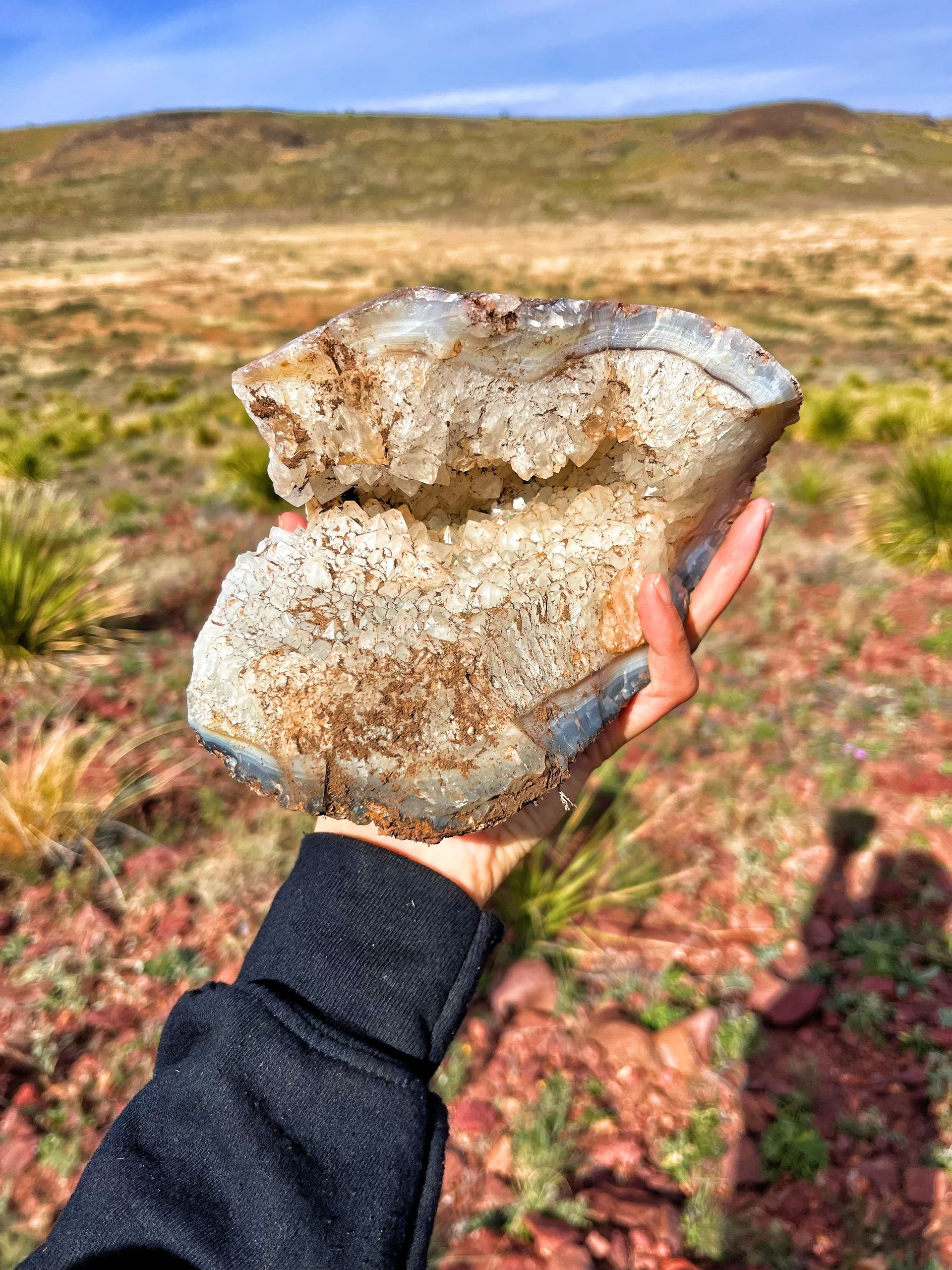 Silhouette of a person in a suspended tent on a cliff at sunset, ropes attached.