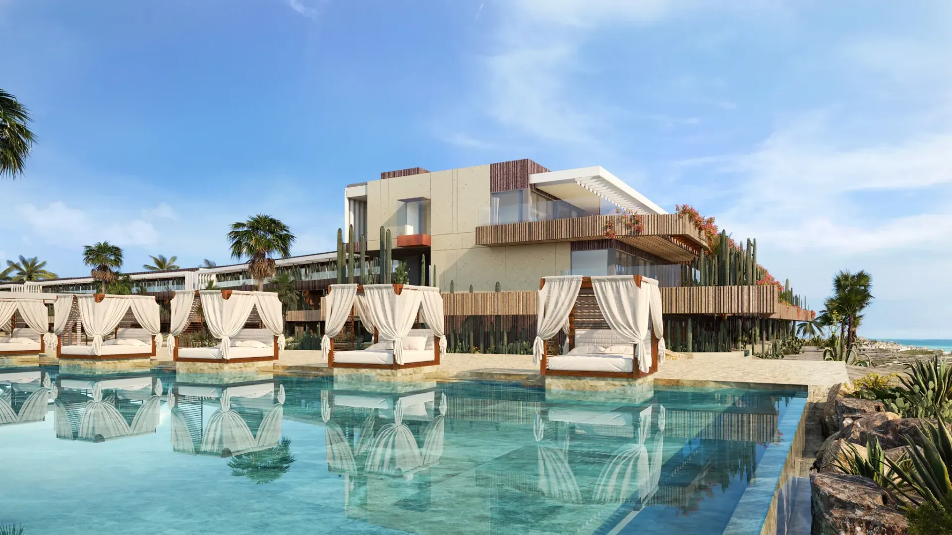 Luxurious resort with cabanas by a pool, overlooking the ocean. Building with wooden accents, blue sky.