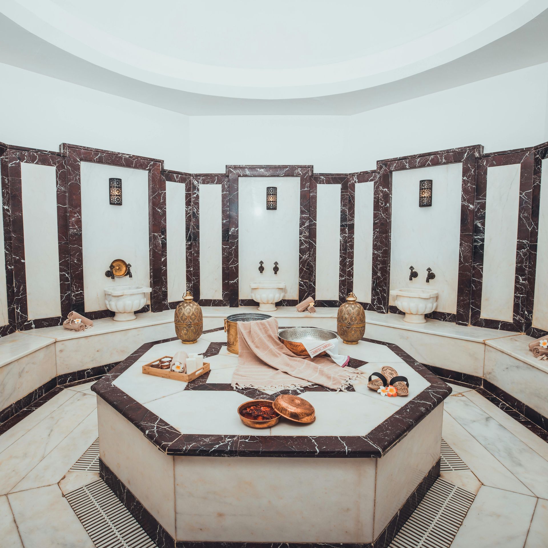Spa interior with marble, octagonal tub, and ornate fixtures.