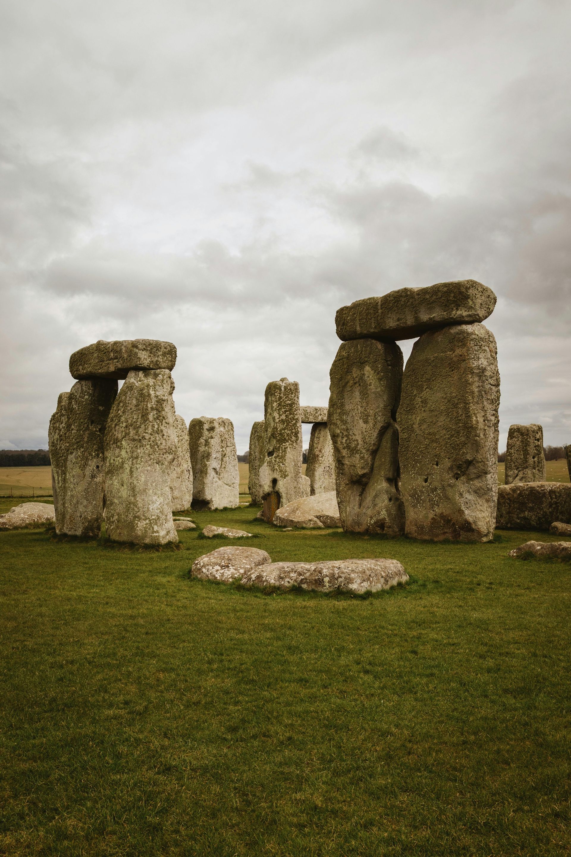 Stonehenge, ancient stone circle in a green field, cloudy sky.