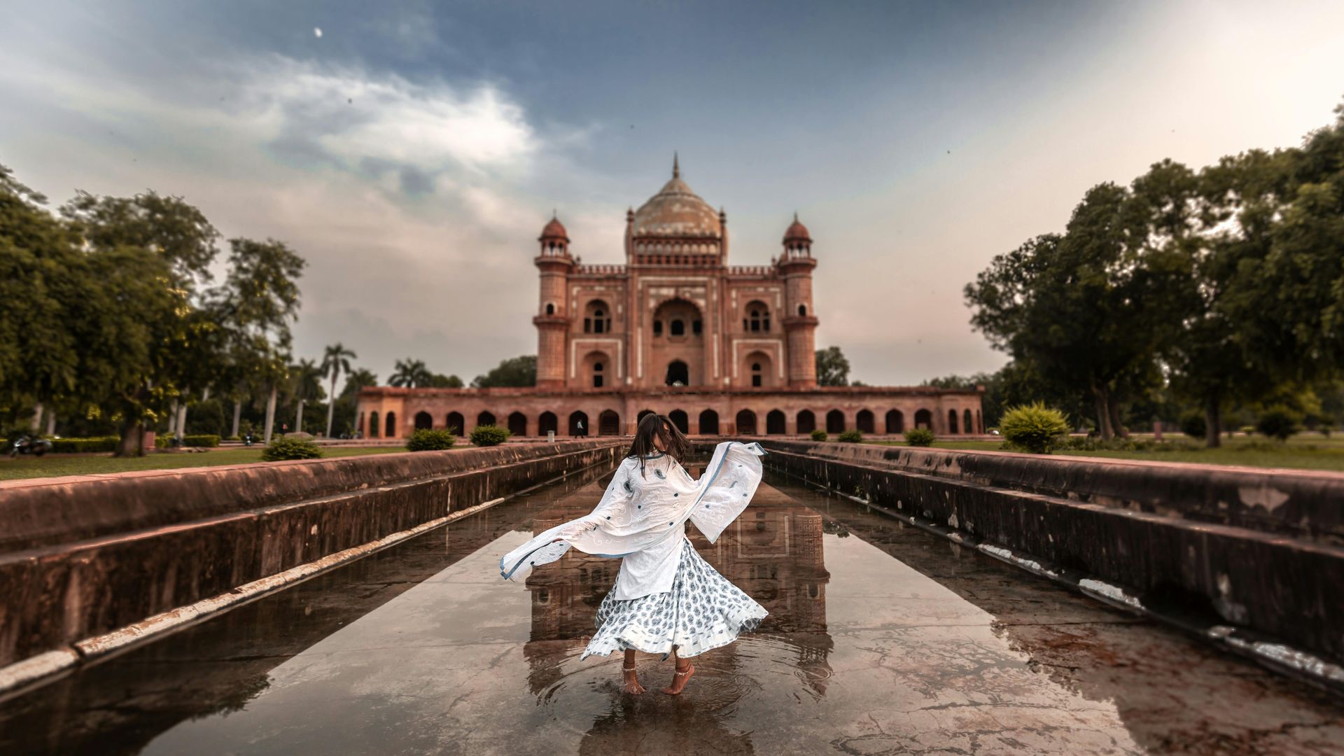 Woman in white dress dancing in front of Safdarjung Tomb, New Delhi.