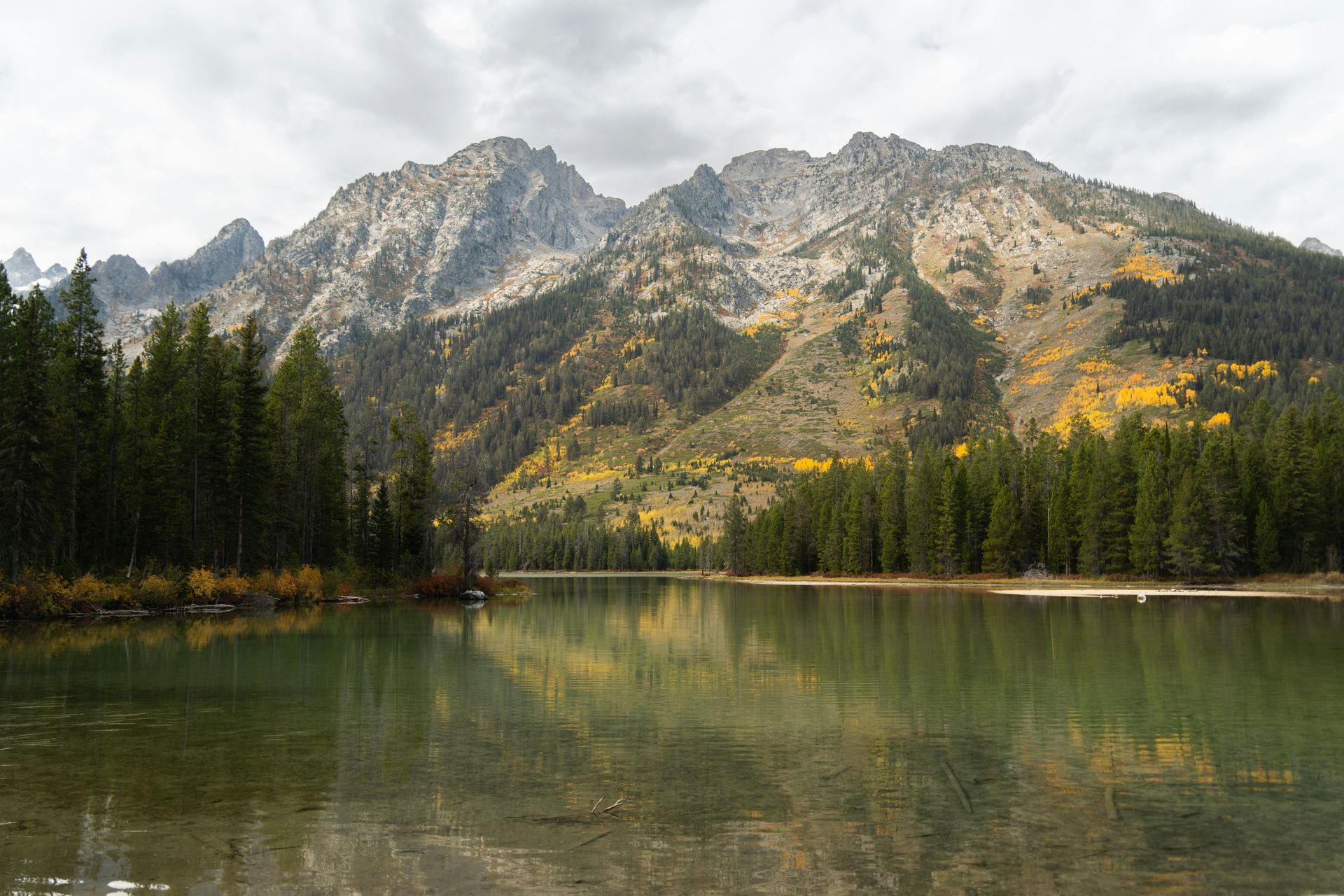 Three RVs parked on a red-rock cliff overlooking turquoise water.