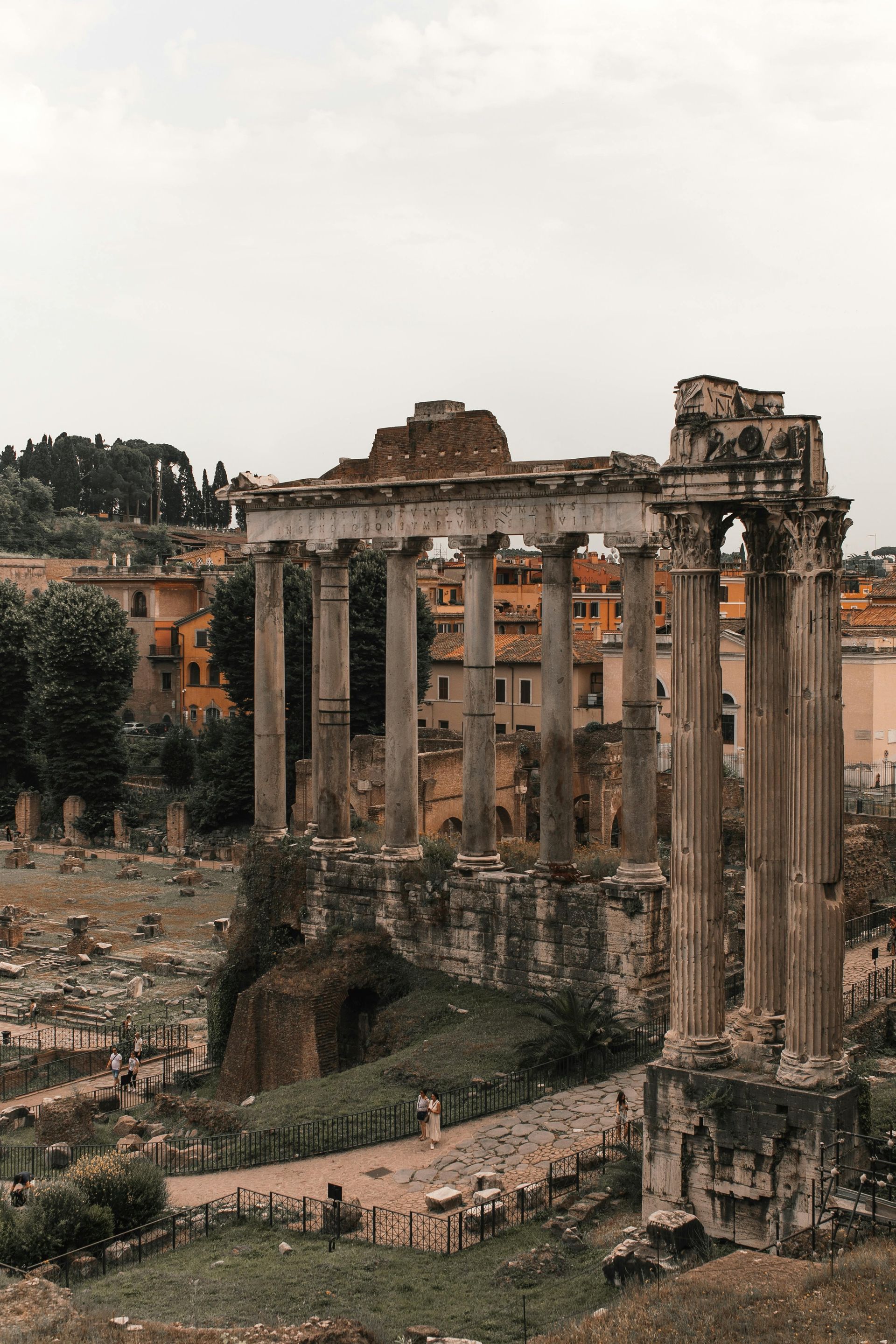 Ruins of ancient Roman columns and buildings in a historical setting. Overcast sky.