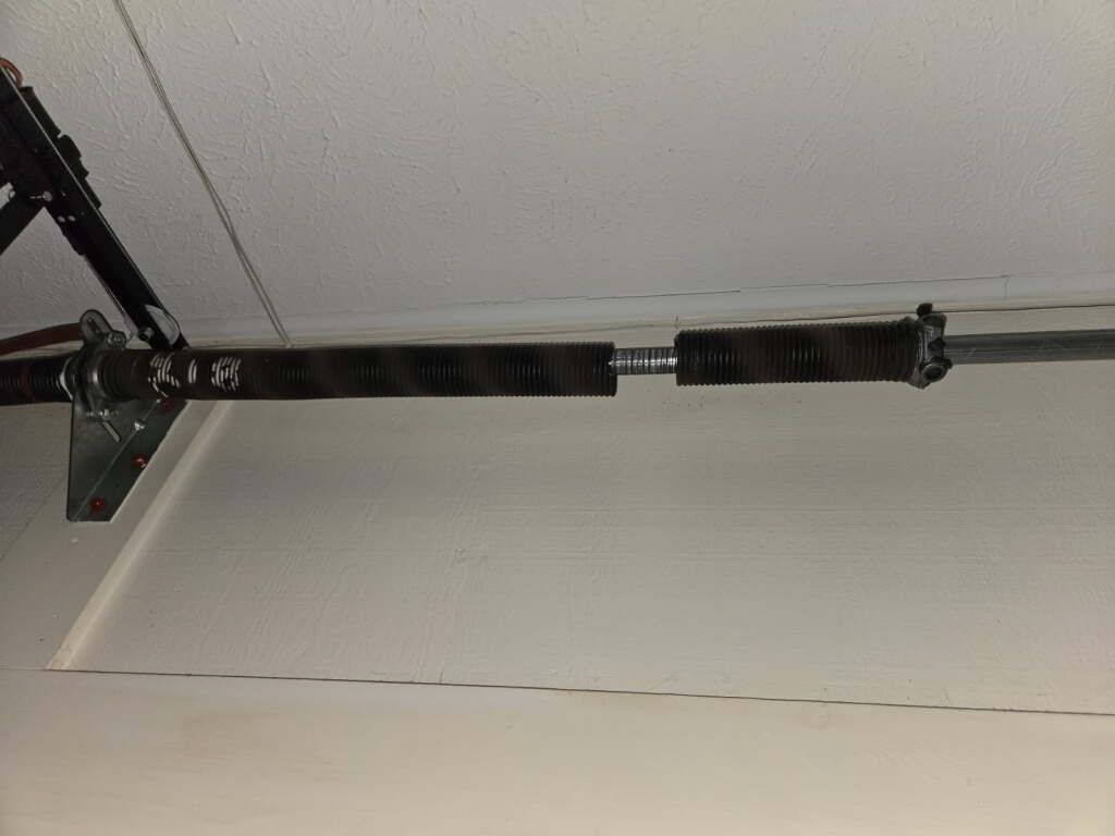 Garage door spring and track mounted to the ceiling, viewed from below.