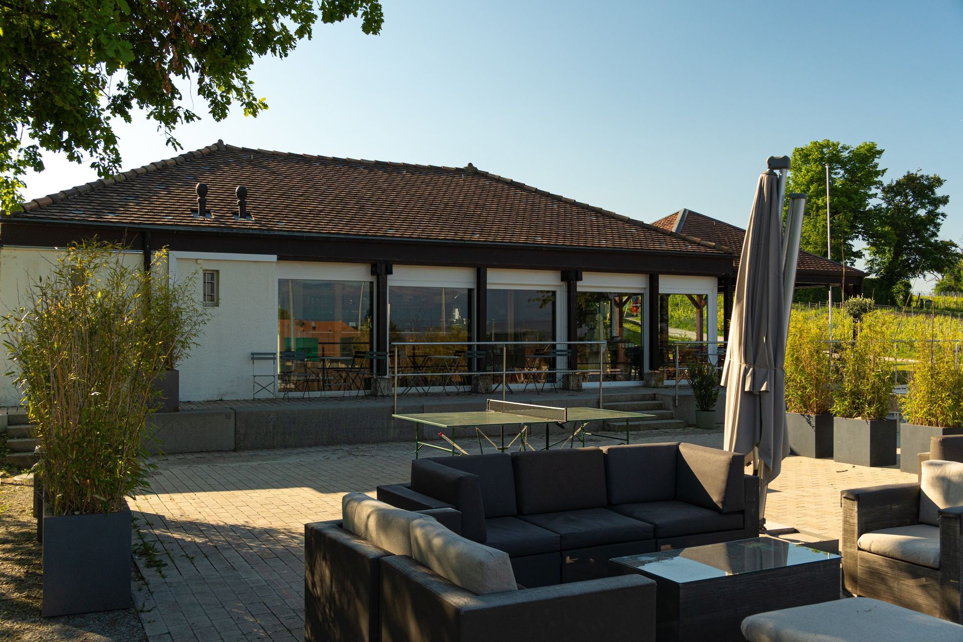 Un patio avec un canapé et un parasol devant une maison