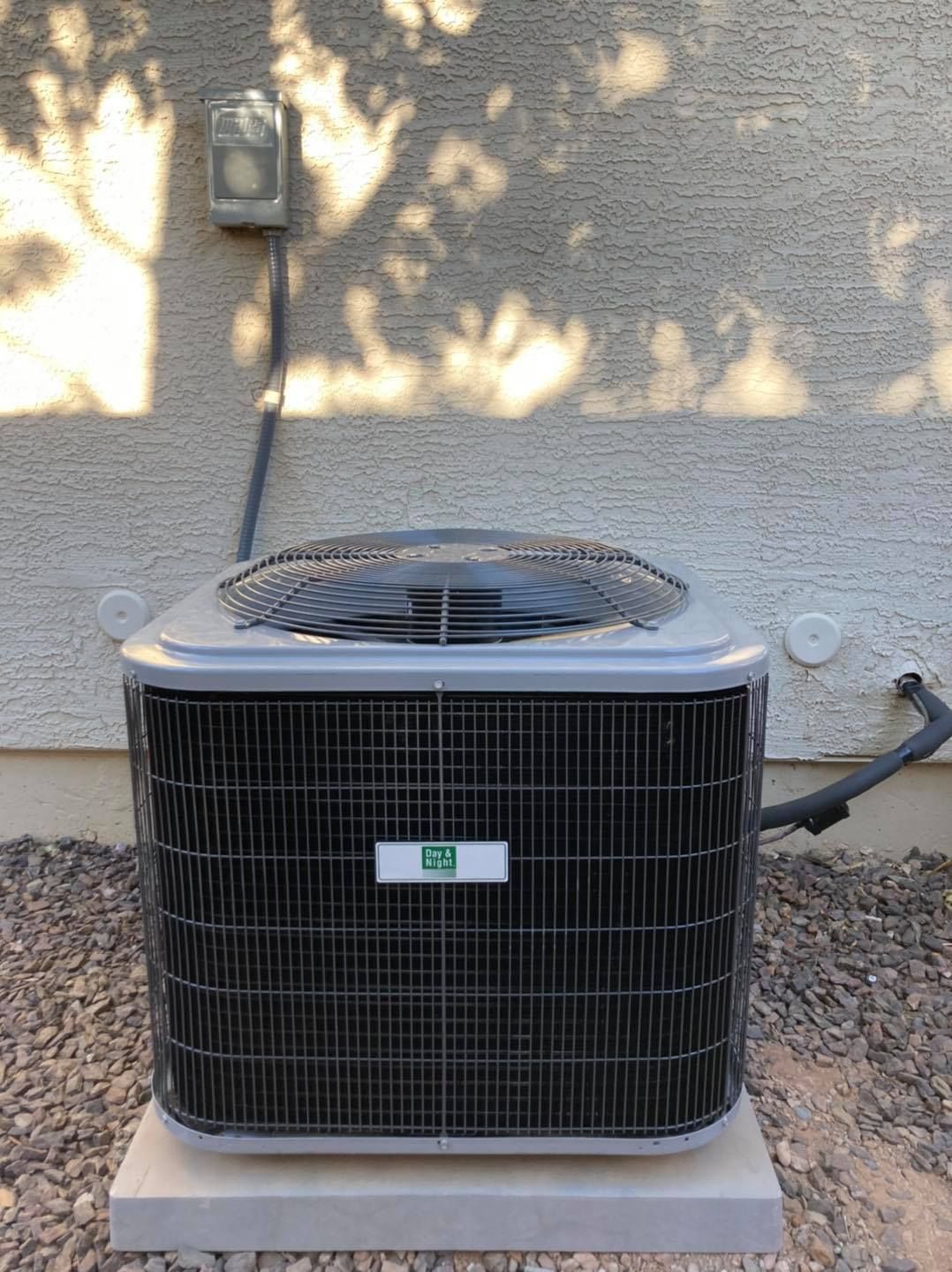 A large air conditioner is sitting outside of a house.