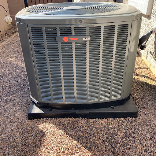 A large air conditioner is sitting on top of a gravel driveway.