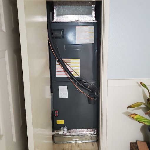 An air conditioner is sitting in a closet next to a plant.