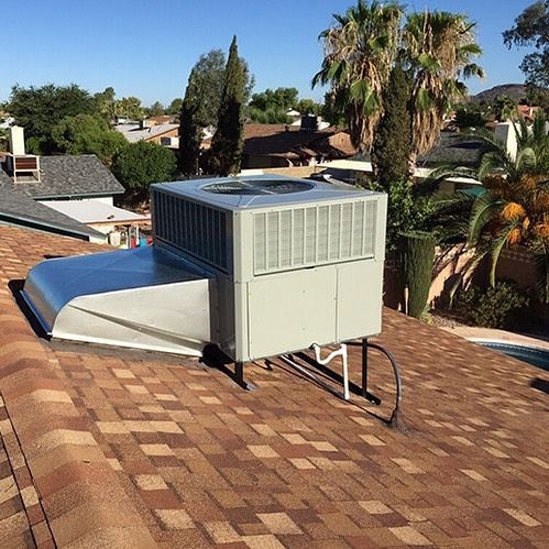 A large air conditioner is sitting on top of a brick roof.