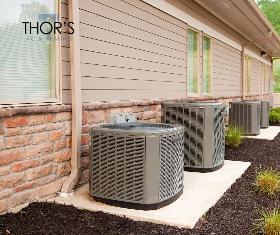 A row of air conditioners are sitting outside of a house.
