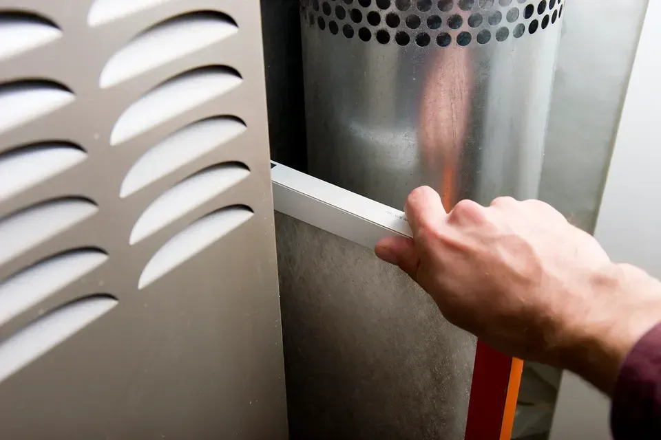 A person is changing a filter on a furnace.