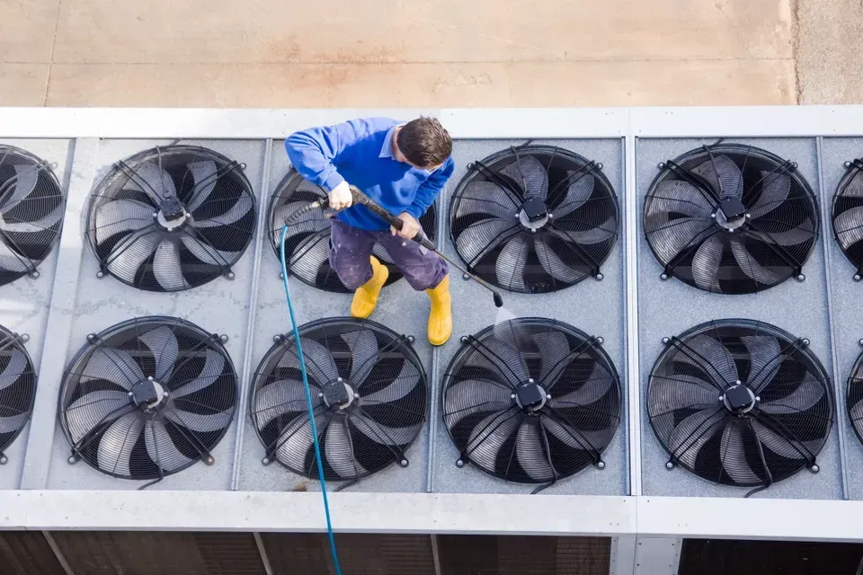A man is cleaning the roof of a building with a high pressure washer.