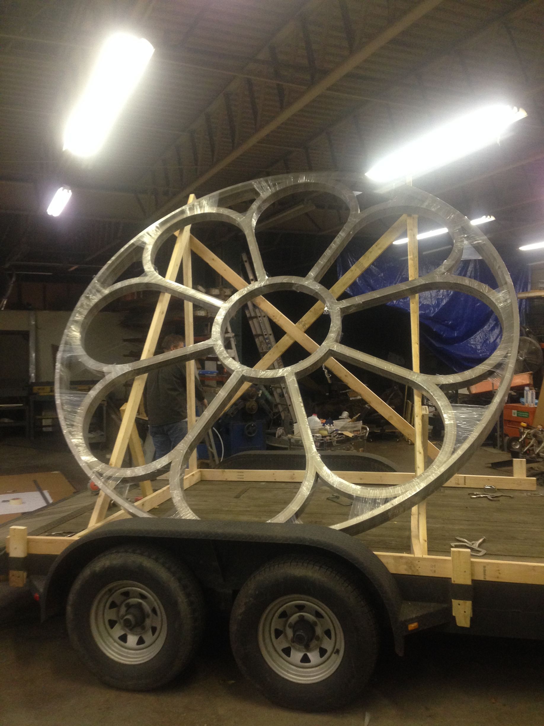 A large metal wheel is sitting on top of a trailer.