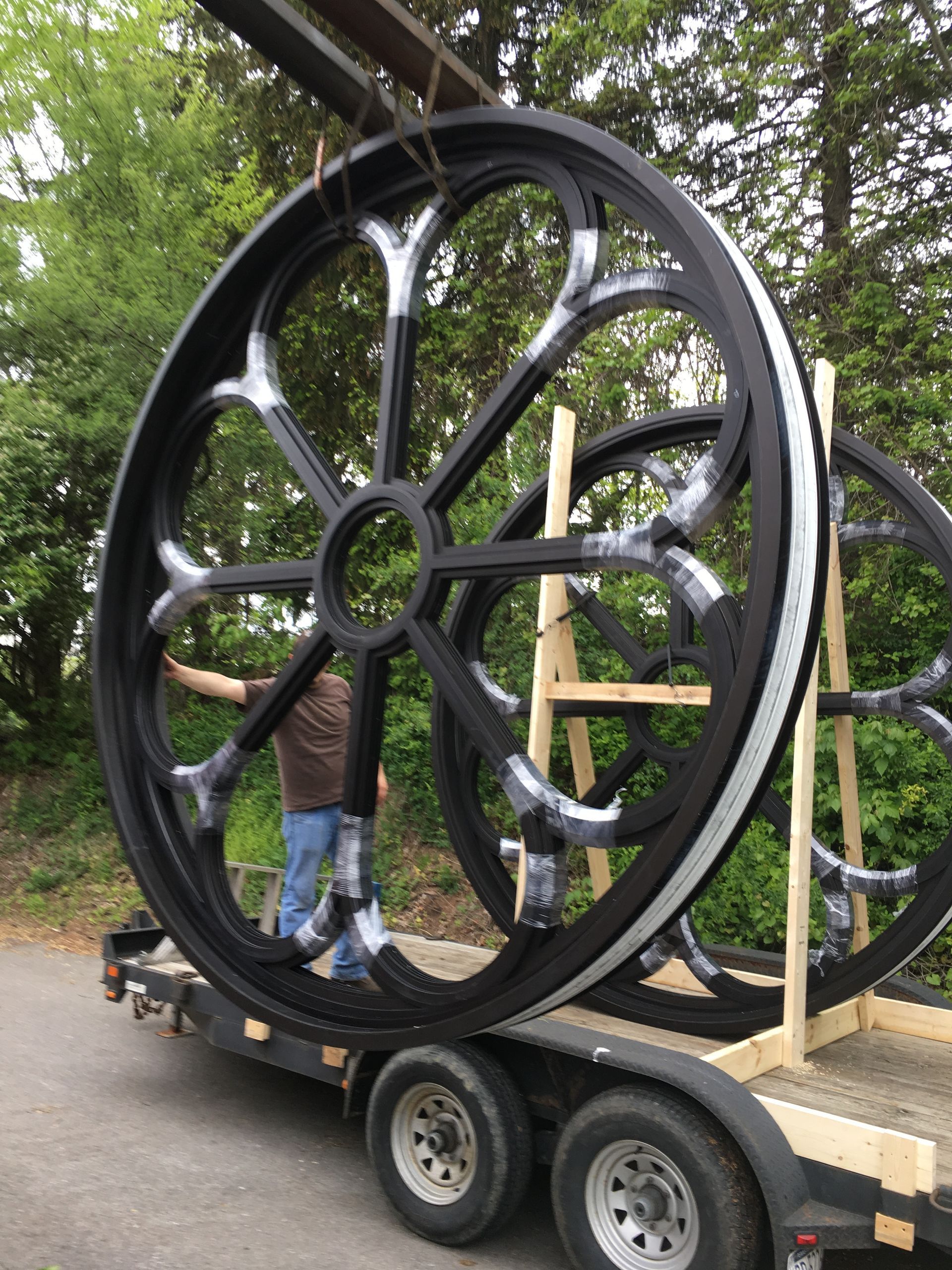 A man is holding a large wheel on a trailer