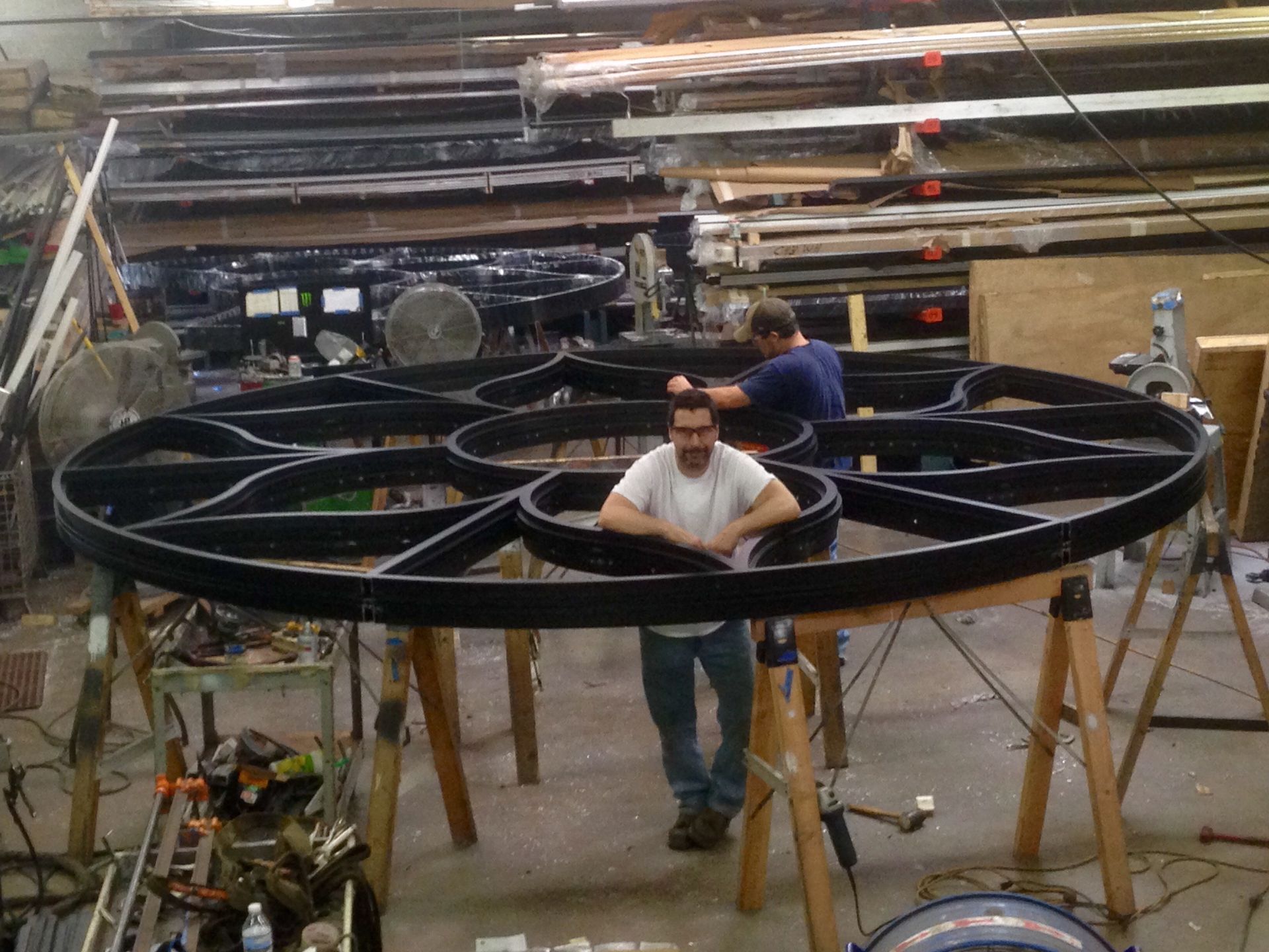 A man is standing in front of a large black wheel