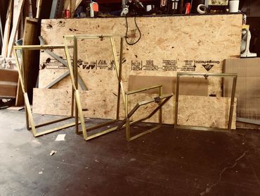 A group of metal frames are sitting on the floor in front of a wooden wall.