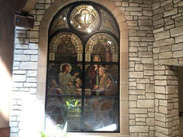 A stained glass window in a church with a stone wall behind it