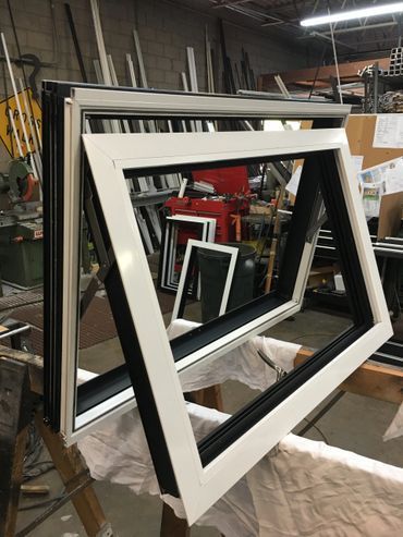 A black and white window frame is sitting on a table in a workshop.