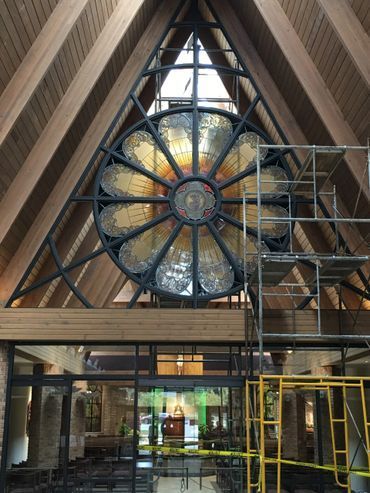 A large stained glass window is hanging from the ceiling of a building.