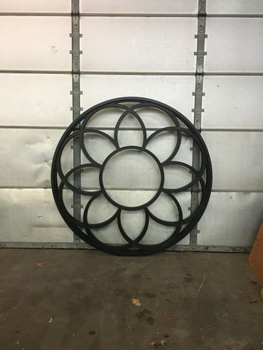 A black metal flower is sitting in front of a garage door.