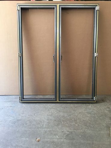 A window frame is sitting on a concrete floor next to a wall.