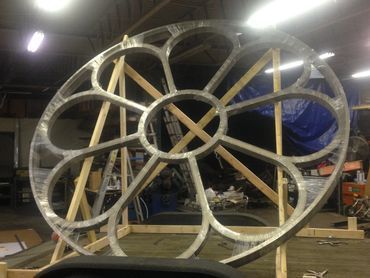 A large metal wheel is sitting on a wooden stand