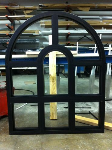 A black window with a wooden frame is sitting on the floor