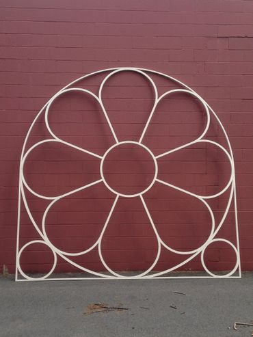 A white flower shaped frame is against a red brick wall