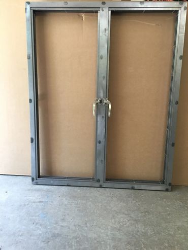 A metal window frame is sitting on top of a wooden table.