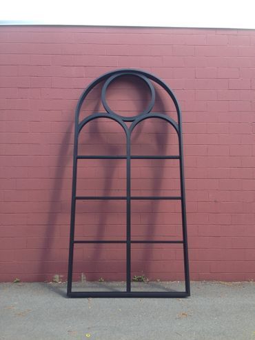 A large black window frame is sitting in front of a red brick wall.