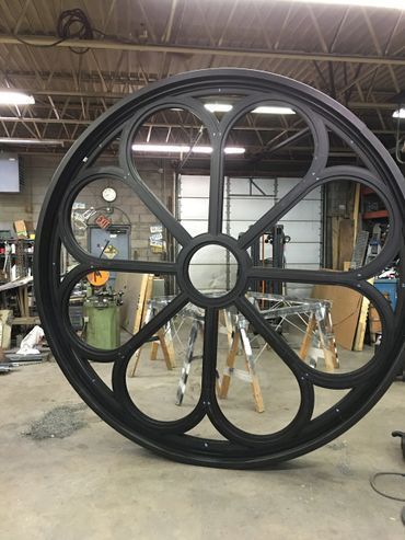 A large black wheel is sitting in a room in a factory.
