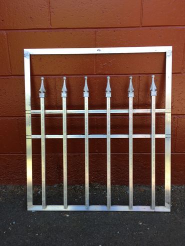 A metal gate is sitting in front of a red brick wall.