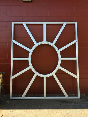 A white frame with a circle in the middle is sitting in front of a red brick wall.