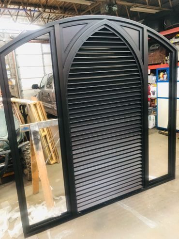 A large window with shutters on it is sitting in a garage.