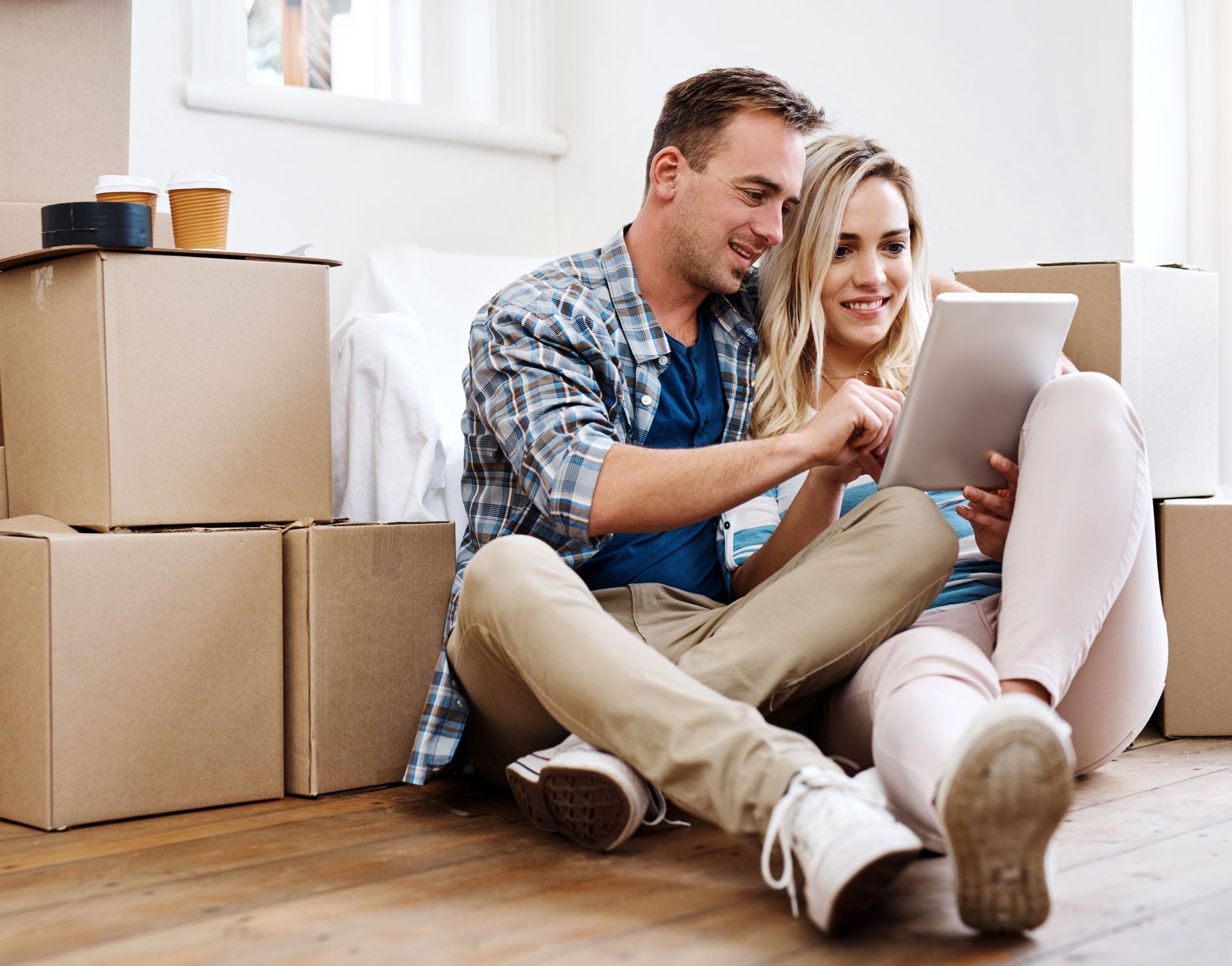 a couple sitting with a tablet with packed moving boxes