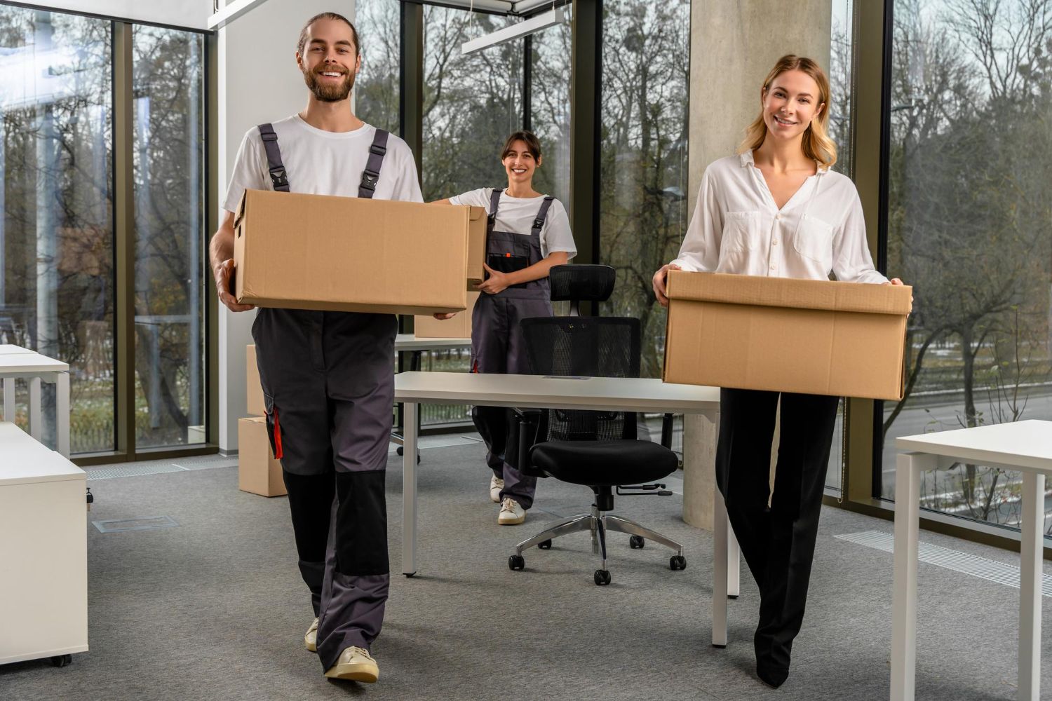 A group of people are carrying cardboard boxes into an office.