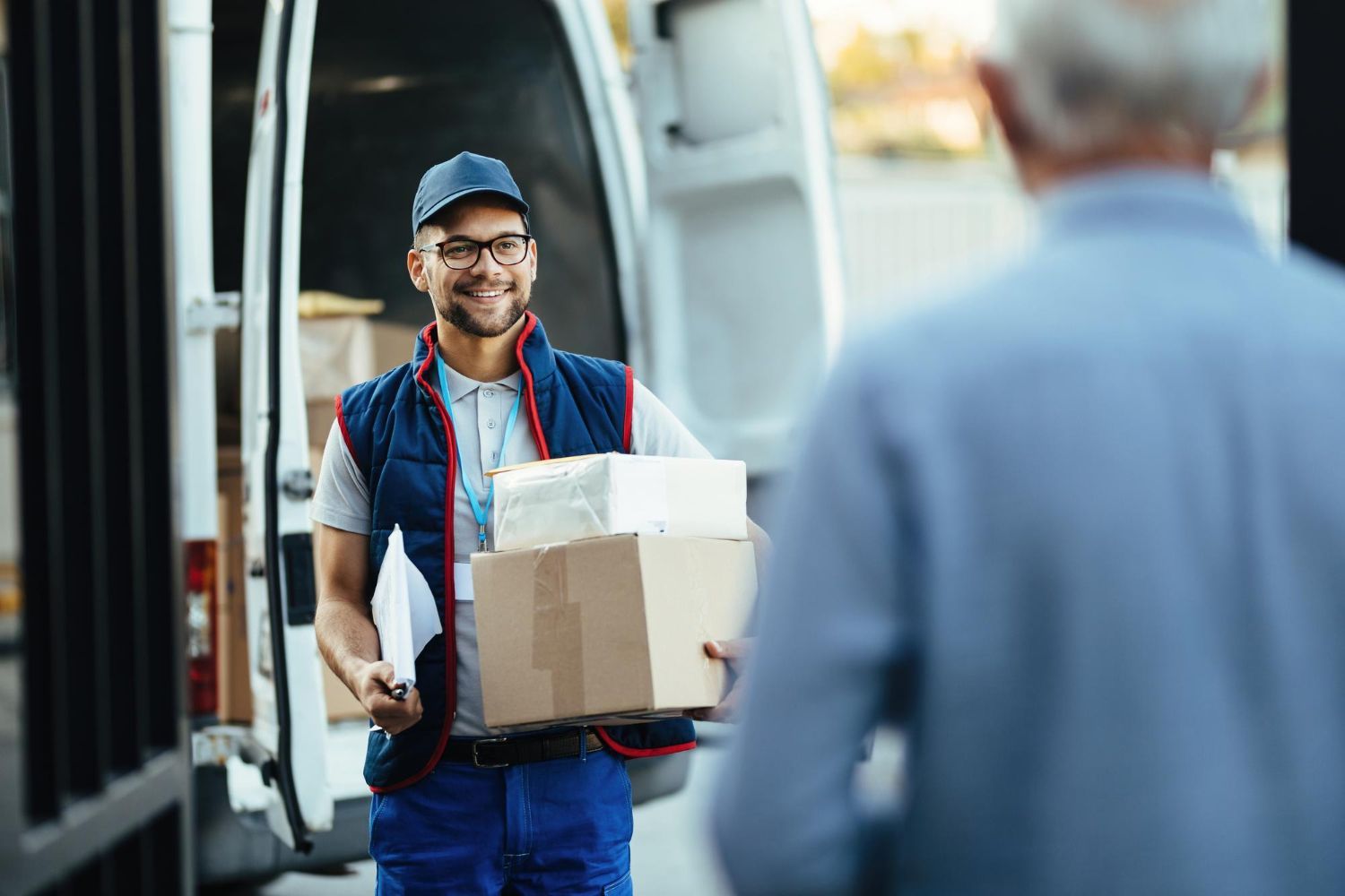 A delivery man is carrying a box to an elderly man.