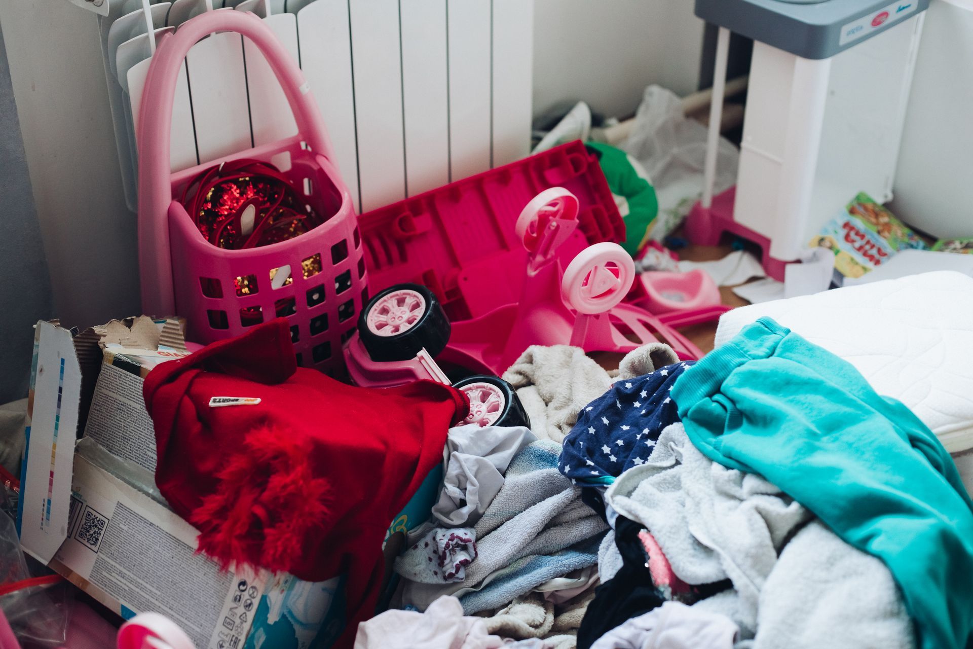 A pile of clothes and toys on the floor in a messy room.