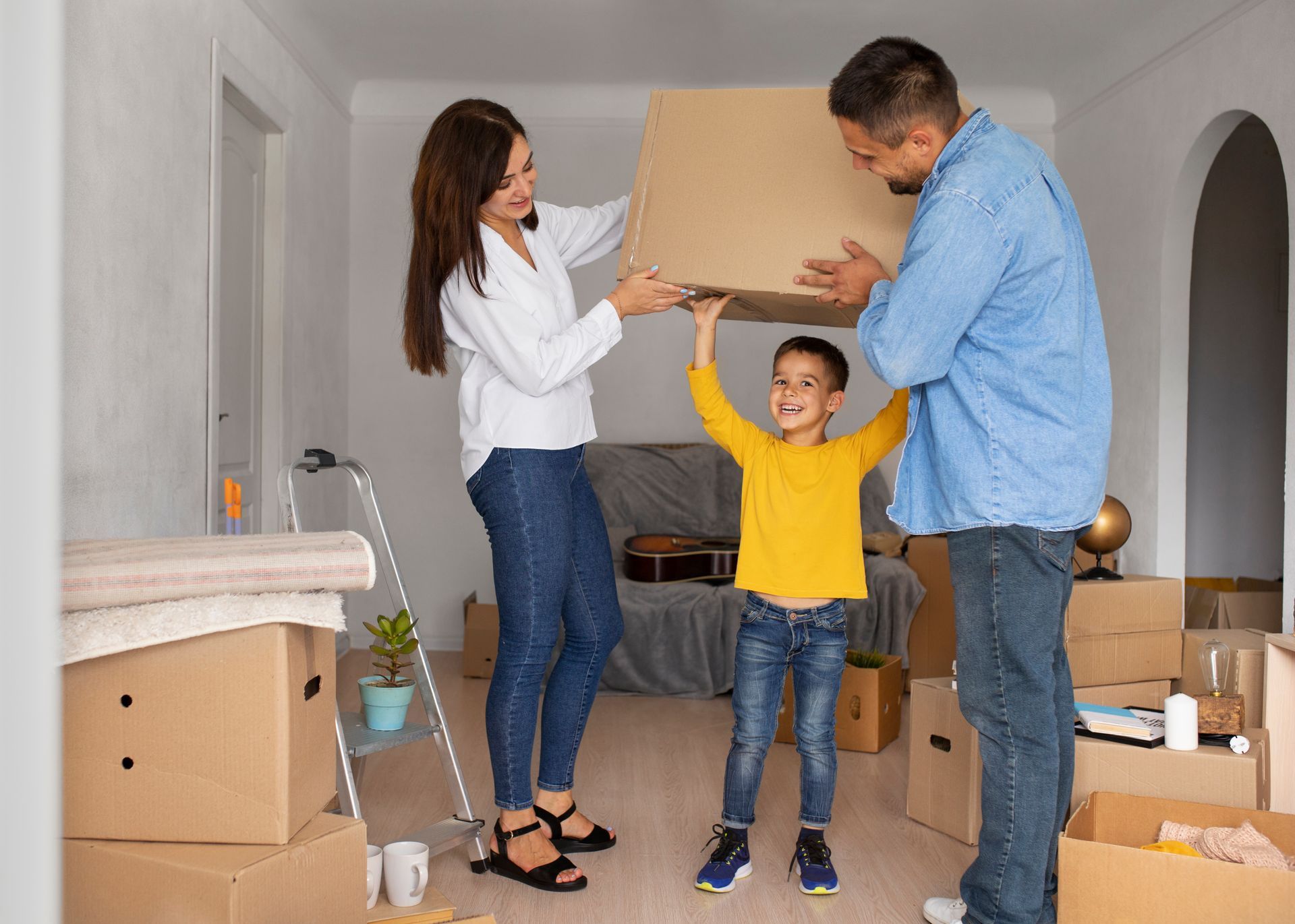 A family is moving into a new home and holding a cardboard box.