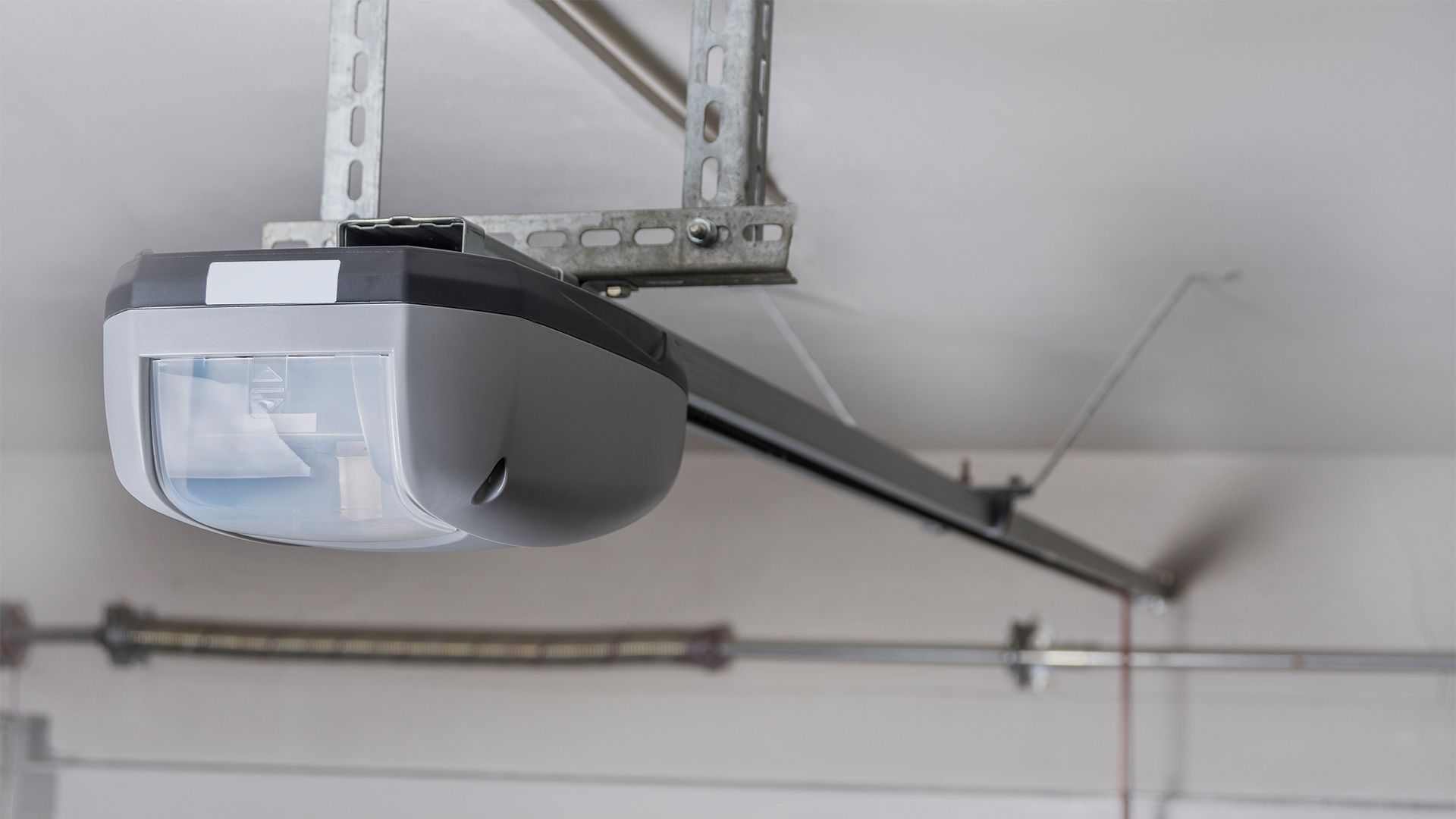 A garage door opener is hanging from the ceiling of a garage.