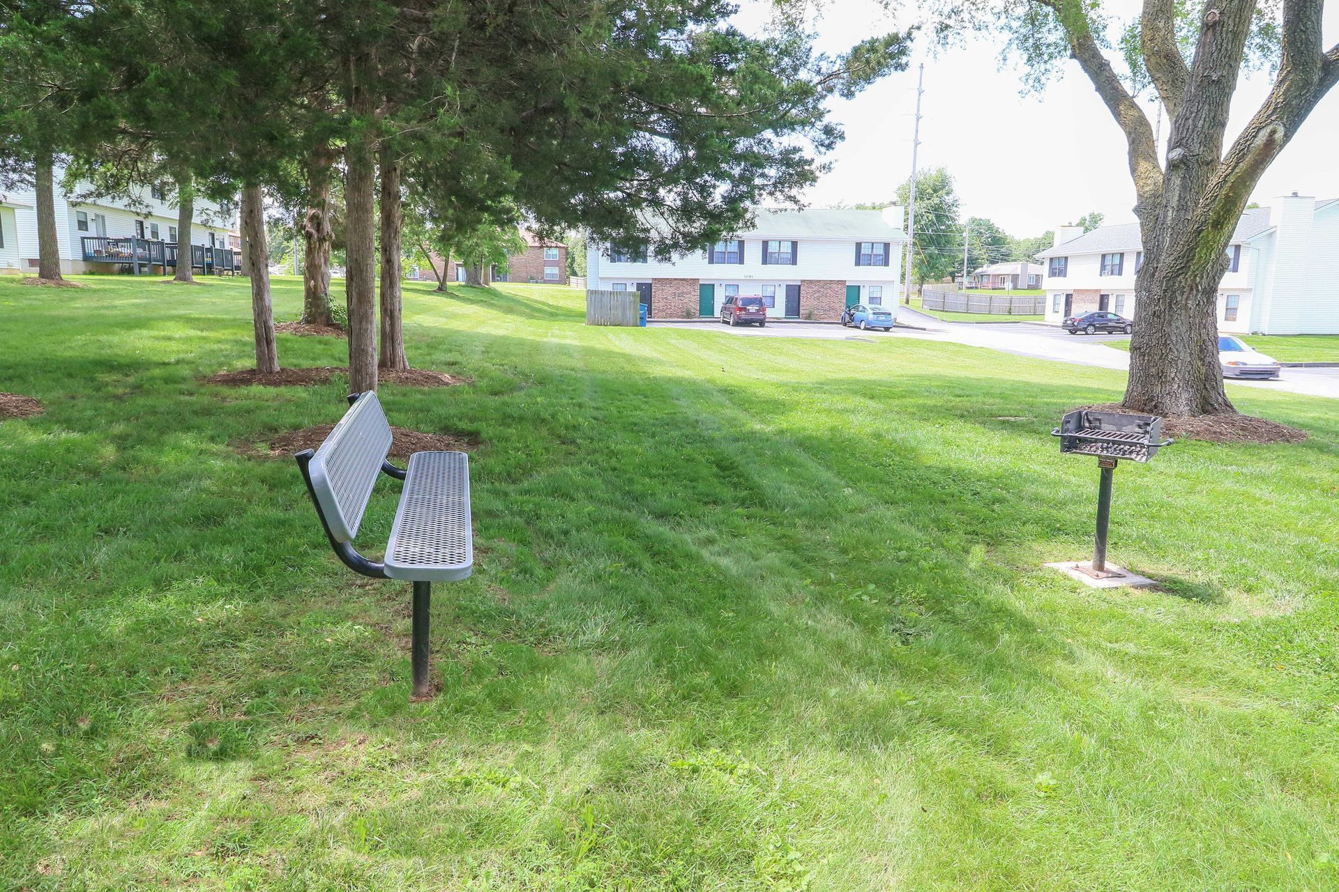 A park bench is sitting in the middle of a lush green field.