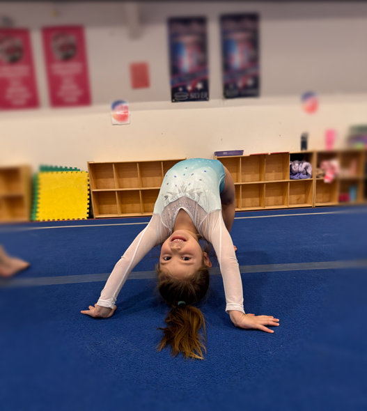 A little girl is doing a handstand on a blue mat