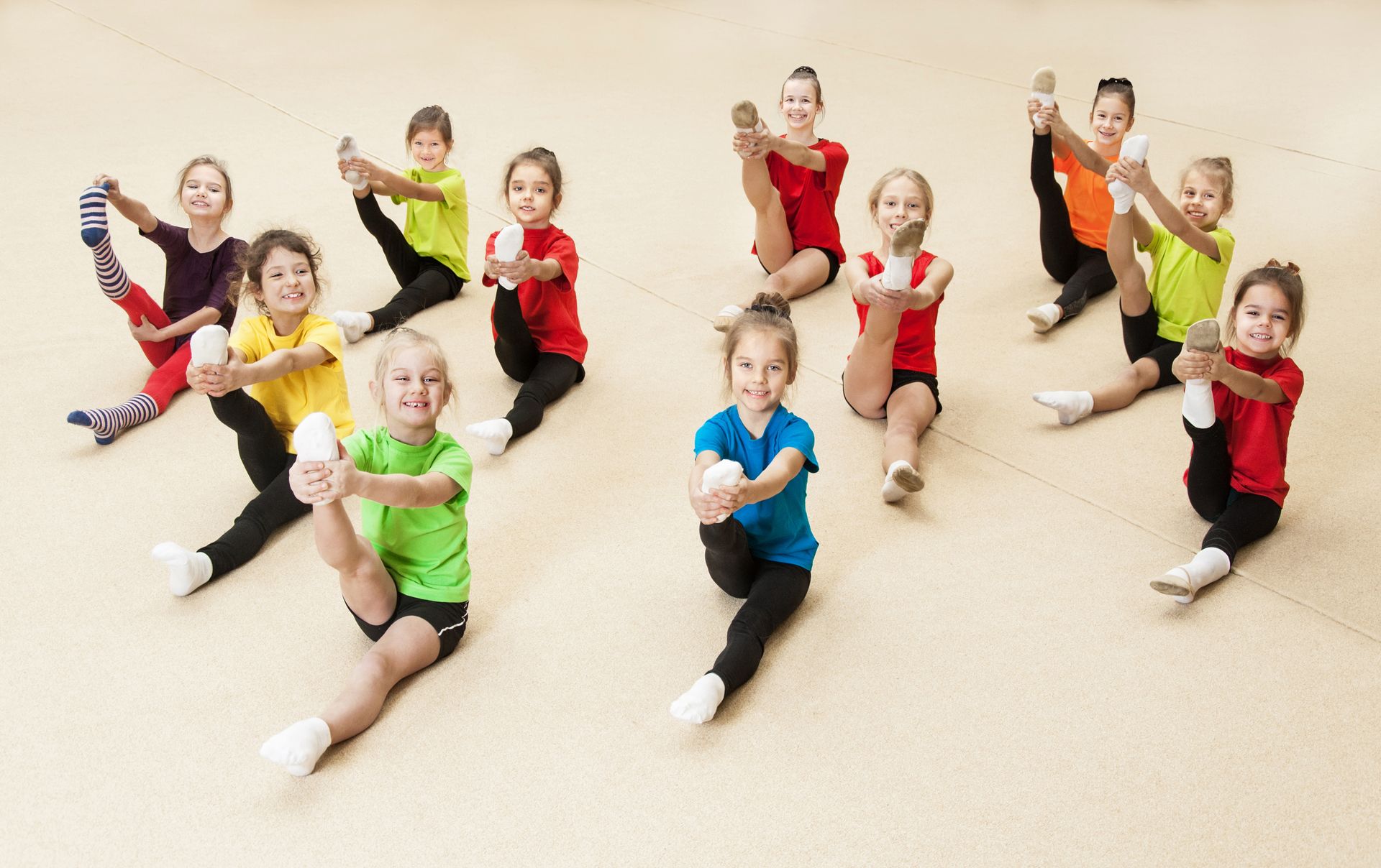 A little girl is doing a split on a blue mat