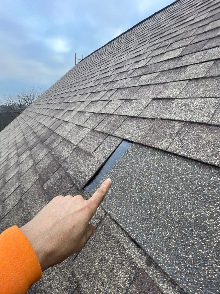 A person is pointing at a hole in a roof.