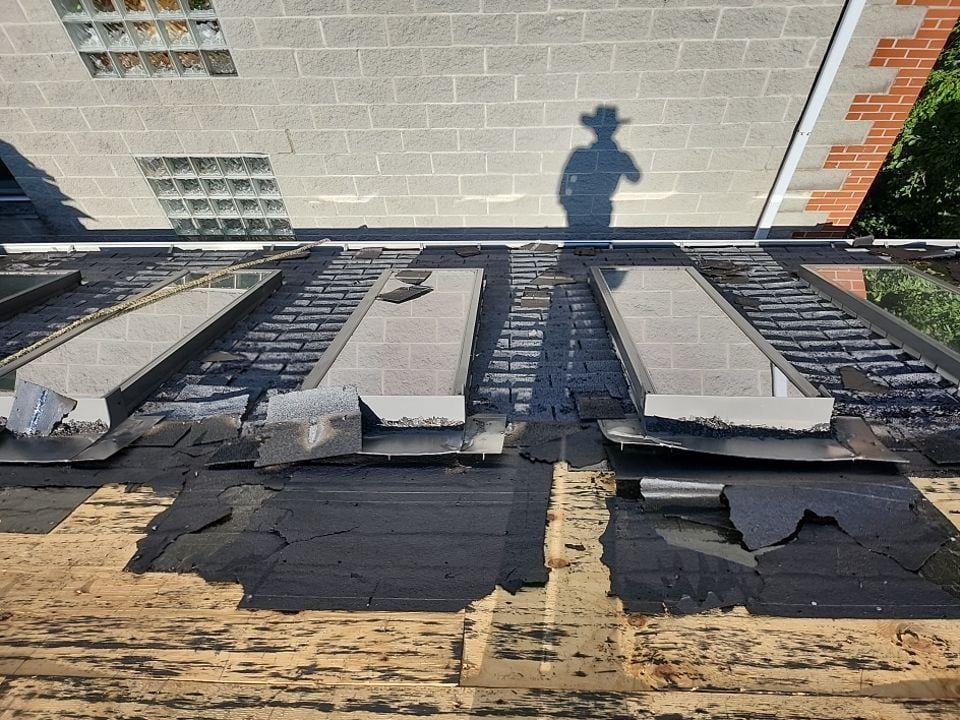 A shadow of a man in a hat is cast on the roof of a building