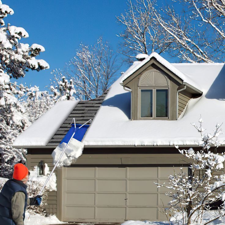 A man is shoveling snow from the roof of a house