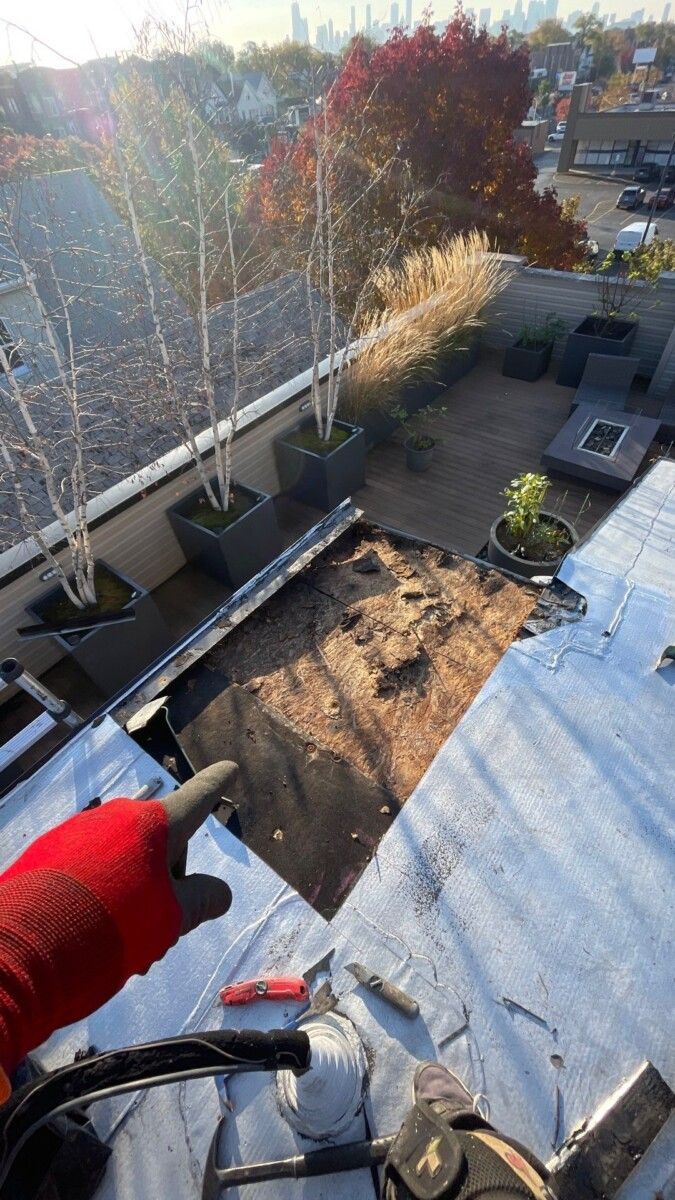 A person wearing red gloves is working on a roof.