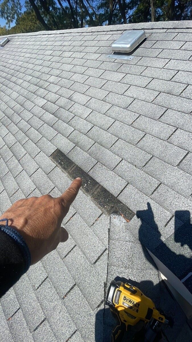 A person is pointing at a hole in the roof.