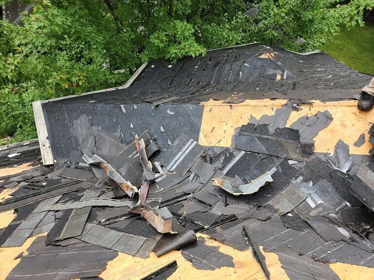 A roof with a lot of shingles laying on the ground.