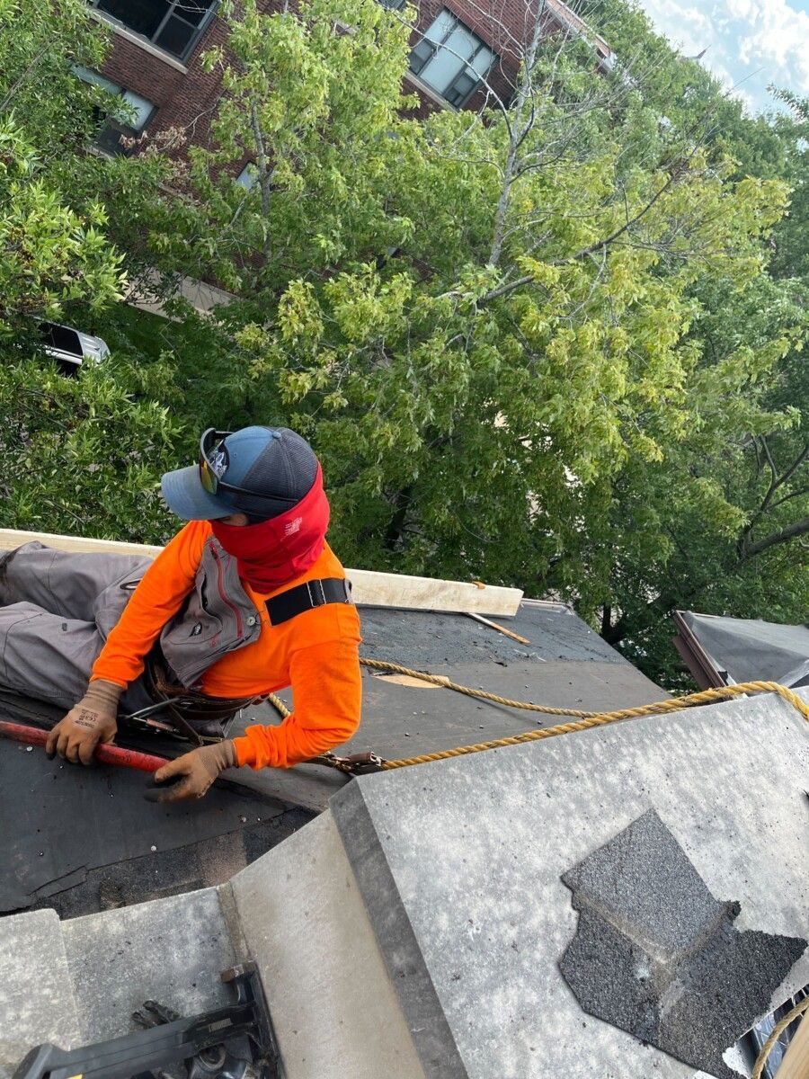 A man is sitting on top of a roof working on it.